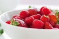 Summer fresh red juicy fruits Ã¢â¬â raspberries and strawberries in a white bowl on a table for breakfast or lunch Royalty Free Stock Photo